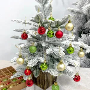 Kleine beflockte Weihnachtsbaum mit bunten Weihnachtskugeln, ideal für die Tischdekoration.