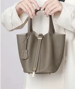 Taupe leather bucket bag close-up showing padlock detail, double handles and soft texture.