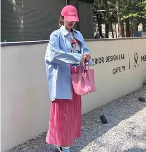 Outdoor detail shot of a pink PU bucket handbag, stylish casual outfit matching.