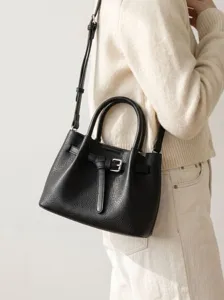 Black leather tote bag with top handle and stylish metal buckle closure for women.