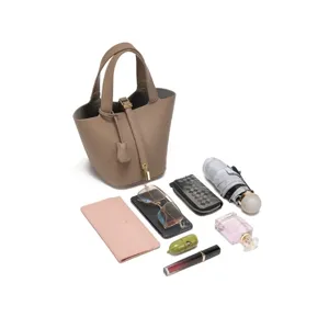 Detail view of minimalist PU leather bucket bag with everyday essentials displayed around.