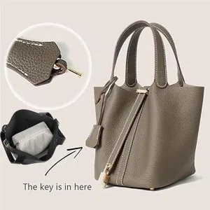 Detailed view of grey PU leather bucket handbag, classic design with lock and interior pouch.