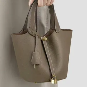 Taupe PU leather bucket bag detail, classic padlock and key charm design, elegant handbag.