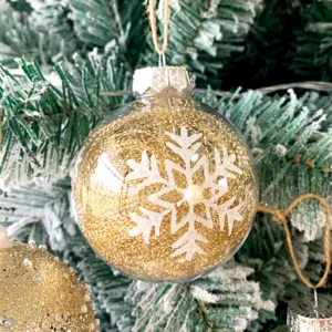 Detailansicht der 8cm transparenten Weihnachtskugel mit Goldglitter und Schneeflocke.