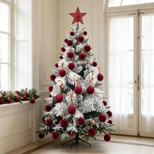 Nahaufnahme eines beflockten Weihnachtsbaumes mit roten Samtkugeln im frohen Innenbereich.