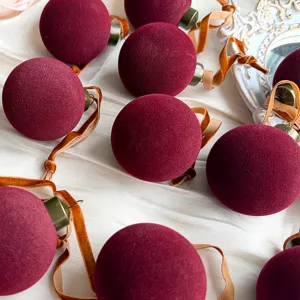 Nahaufnahme von bordeauxroten Samt Weihnachtskugeln mit goldenen Bändern für die Dekoration.