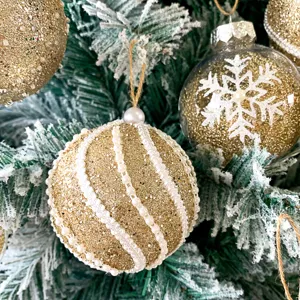 Nahaufnahme von goldenen Glitzer-Weihnachtsbaumkugeln mit Perlenperlen und Schneeflocken-Details.