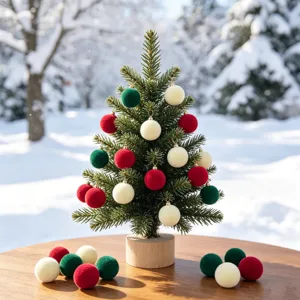 Kleine Weihnachtsbaum Tischdekoration mit Samt beflockten Kugeln für die feierliche Detailansicht.