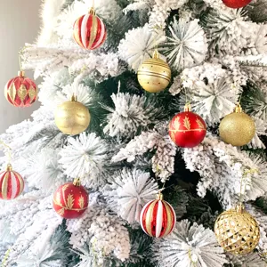 Detailansicht von Weihnachtsbaumkugeln, rot-gold lackierte Kugeln im verschneiten Tannenbaum.
