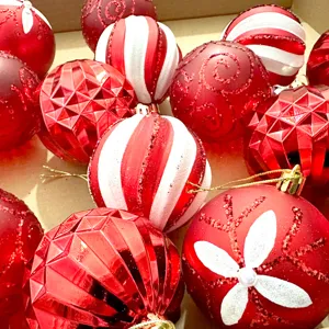 Nahaufnahme von roten und weißen Christbaumkugeln mit Glitzer und facettierten Mustern.