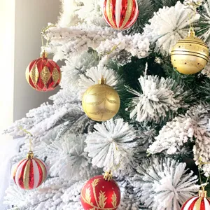 Detaillierte Nahaufnahme von bunten Christbaumkugeln hängend an verschneiten Ästen.