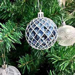 Detailaufnahme einer blauen Mosaik Weihnachtskugel hängend an künstlichem Weihnachtsbaum.