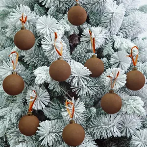 Braune beflockte Samt Weihnachtskugel Dekoration Detail hängend am schneebedeckten Baum.