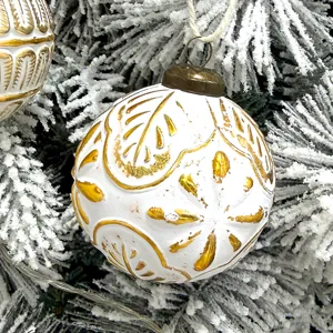 Detaillierte Nahaufnahme einer weißen und goldenen geprägten Vintage-Weihnachtskugel.