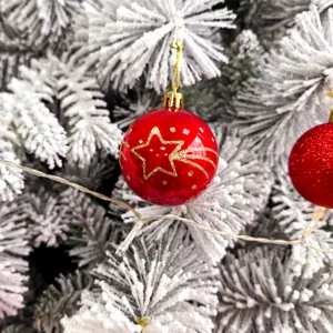 Nahaufnahme Detail einer glänzenden roten Weihnachtskugel mit goldenem Glitzerstern Motiv.