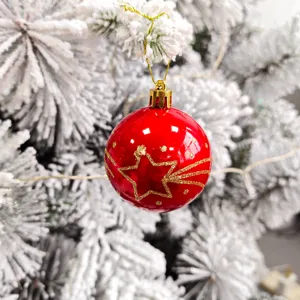 Nahaufnahme einer roten Weihnachtskugel mit goldenem Glitzer-Sternmotiv am Tannenbaum.