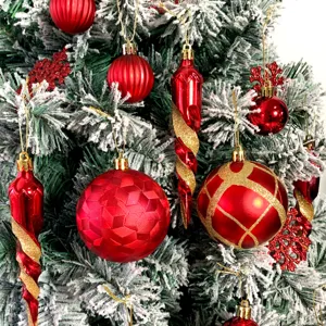 Nahaufnahme von roten und goldenen Christbaumkugeln, hängend an bemalten Tannenzweigen.