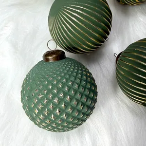 Grüne weihnachtliche Dekokugeln mit goldenen Reliefmustern für festlichen Christbaum.
