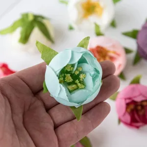 Nahaufnahme künstlicher blauer Rosenblütenköpfe für DIY-Girlanden und Geschenkkarton-Dekor.