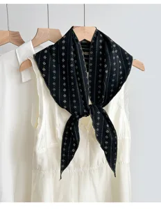Detailaufnahme eines vintage-schwarzen gemusterten Baumwollmisch-Dreieckstuchs an einem weißen Kleid.