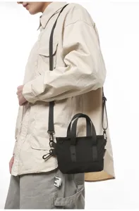 Model wearing a small black minimalist crossbody bag with adjustable straps