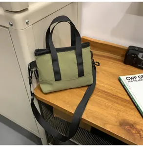 Olive green minimalist small crossbody bag displayed on a wooden table with camera