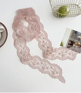 Detail d'echarpe ruban etroite et longue en dentelle brodee florale rose, accessoire.