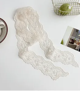 Vue rapprochée d'un élégant foulard étroit en dentelle écru avec broderie florale délicate.