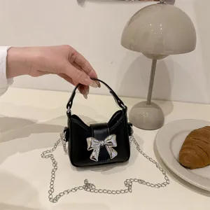 Cute black mini shoulder bag with silver bow and chain strap, perfect detail view for girls.