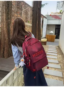 Λεπτομέρεια εξωτερικής σκηνής με κομψό κόκκινο σακίδιο πλάτης και χαριτωμένο μενταγιόν.