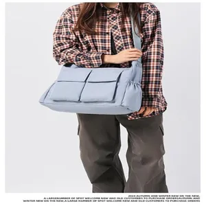 Dettaglio borsa a tracolla in tela con design a tasche multiple e spallaccio.