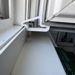 Detailed view of white 3D printed window wedge stopper installed on frame for safety.