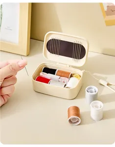 Vue détaillée de la boîte à couture magnétique portable avec fils colorés et accessoires.
