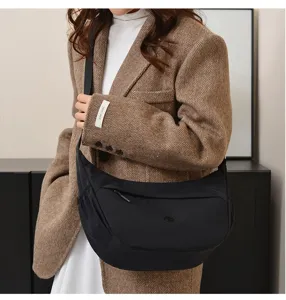 Detailed view of the casual black crescent crossbody bag worn by a model in a chic blazer.