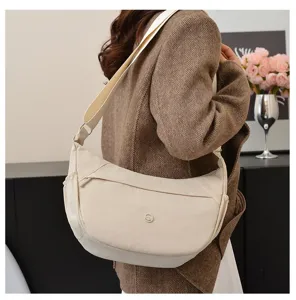 Detail view of the minimalist casual canvas crossbody dumpling bag worn by the model indoors.