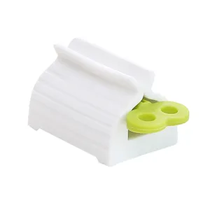 Distributeur de dentifrice en plastique blanc, presse-tube manuel avec poignée verte.