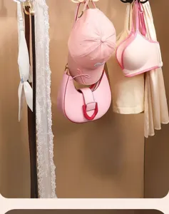 Detailansicht mit rosa Accessoires, Hüten und BHs an einem drehbaren Kleiderschrank-Haken.