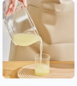 Detail view of glass yogurt strainer cup and wooden tray pouring whey liquid in kitchen use.
