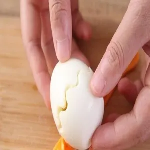 Close-up detail of operating kitchen egg slicer tool on wooden board, easy egg cutting.