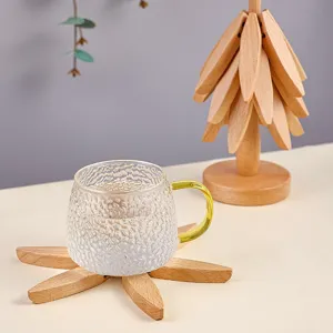 Clear glass cup with green handle and wooden flower coaster for home daily use and desk decor.