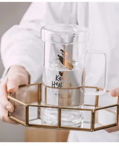 Vue détaillée du mug en verre avec couvercle et anse, imprimé doré, idéal au quotidien.