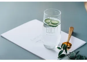 Detail view of Nordic heat-resistant glass cup with water and cucumber, minimalist style for cold drinks.