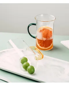 Detailed shot of clear heat-resistant glass cup with colored handle, aesthetic scene setup.