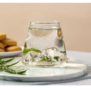 Gros plan du verre style Fuji japonais avec de l'eau claire et un accessoire de feuille verte.