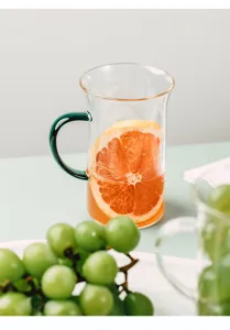 Close-up detail shot of the transparent heat-resistant glass cup with green handle.