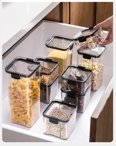 Barattoli alimentari trasparenti in plastica con coperchi neri ermetici nel cassetto.