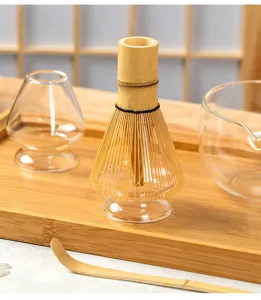 Detailed view of matcha whisk and glass bowl set on wooden tray, natural tea ceremony props.