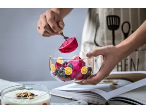 Gros plan sur un bol à dessert en verre transparent avec motif de citron et fruits frais.