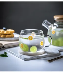 Primo piano dettagliato di una simpatica tazza d'acqua in vetro con motivo di frutta e manico.