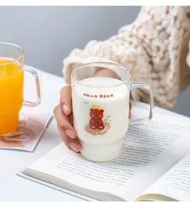 Detalle en primer plano de taza de vidrio transparente con osito y asa cómoda.